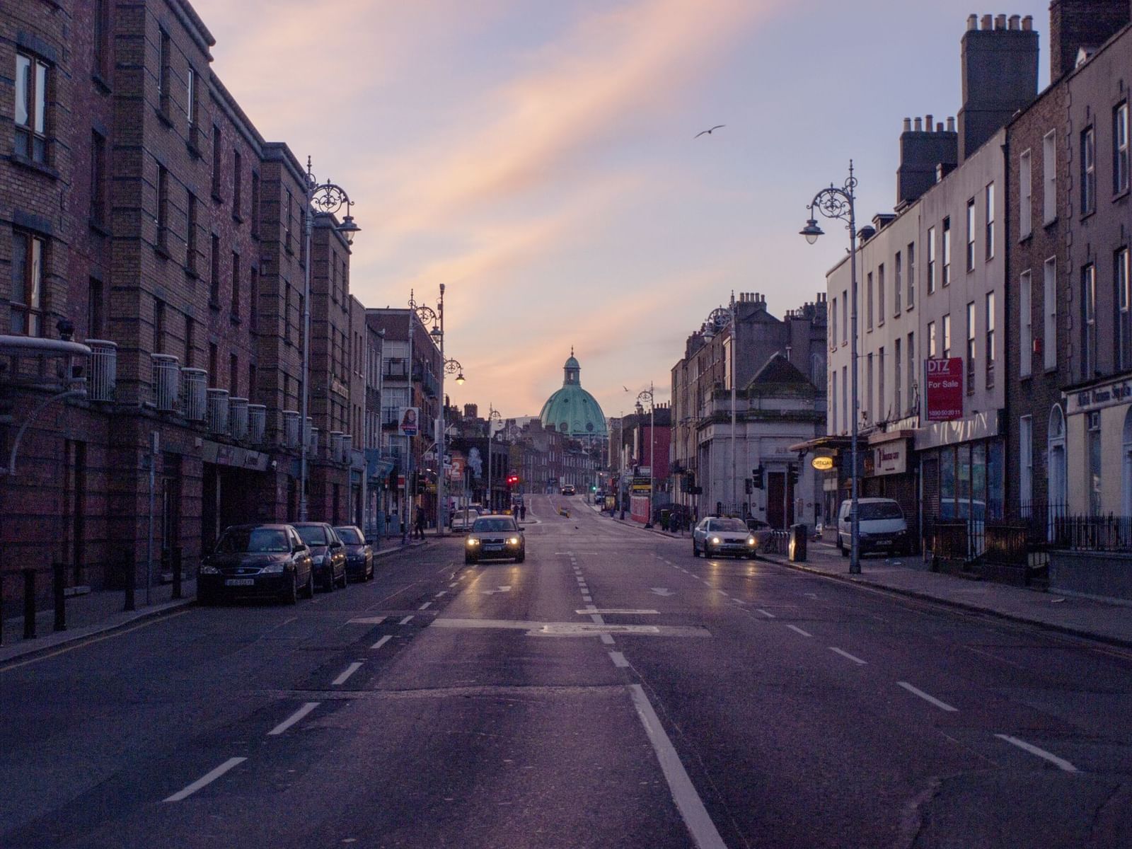 A busy suburban Dublin street with parked cars and traffic